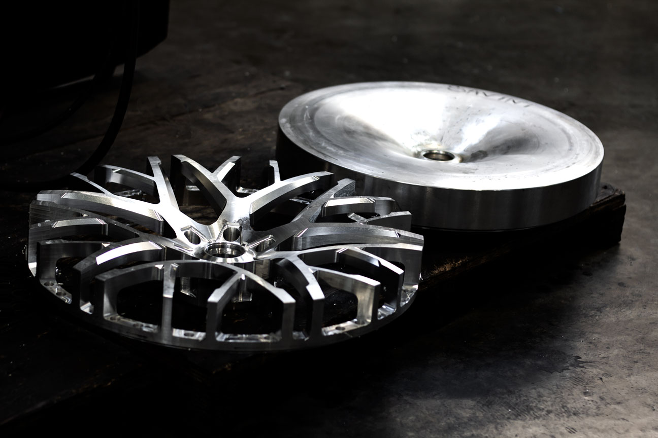 Forged billet blank beside a machined wheel face